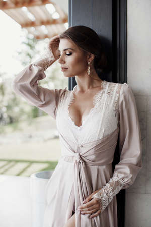 Sexy girl, brunette with beautiful hair, in amazing clothes posing in hotel.Beautiful young woman in a chic pink bathrobe spends time alone in an expensive hotel in the during the holidays.Woman enjoys relaxing in a beautiful hotel on the Red Sea.の写真素材