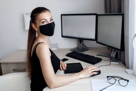 COVID-19 Pandemic Coronavirus Mask Woman Home Working Isolation Laptop Computer Auto Quarantine. Girl wearing face mask smart home working on a home computer against Coronavirus Disease 2019. Compliance with the requirements of the self-isolation modeの写真素材