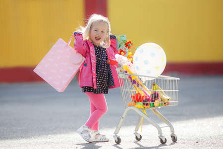 Girl with a big grocery cart in a parking lot near a storeの写真素材