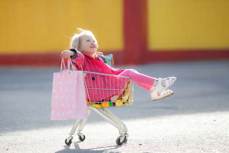 Girl with a big grocery cart in a parking lot near a storeの写真素材
