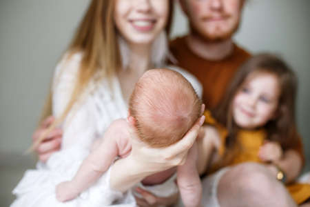 Parenthood, love and family concept - Smiling mother and father holding their baby son. Happy European family, father mother and son baby. Young parents with a newborn son in their arms in the Studio oの写真素材