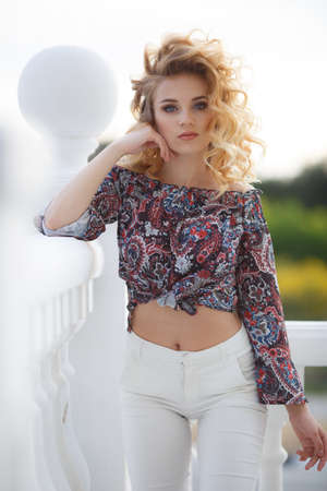 Young beautiful blonde caucasian woman walking summer streets. Beautiful girl, urban portrait.Young attractive woman with perfect smile, summer outdoor portrait. Charming cheerful girl smiling and looの写真素材