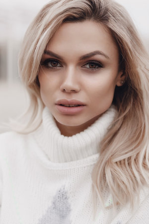 Young beautiful blonde caucasian woman walks alone enjoying the spring weather. Beautiful girl, outdoor portrait. Young attractive woman, spring outdoor portrait. Charming cheerful womanの写真素材