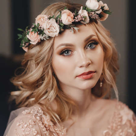 Pretty bride with wedding makeup, fashion jewelry. Beautiful woman posing in white wedding dress. Wedding portrait of happy bride. Bridal fashion model posing in interior. Gorgeous beauty, young brideの写真素材
