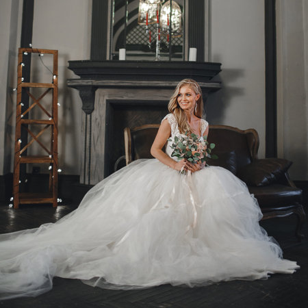 Pretty bride with wedding makeup, fashion jewelry. Beautiful woman posing in white wedding dress. Wedding portrait of happy bride. Bridal fashion model posing in interior. Gorgeous beauty, young brideの写真素材