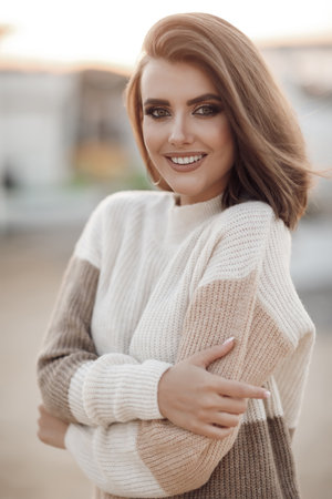 Young woman in a sweater on the sandy coast of an empty beach in the cool weather in early spring. Portrait of a beautiful young model enjoying the day on the background of a deserted beachの写真素材