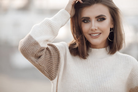 Young woman in a sweater on the sandy coast of an empty beach in the cool weather in early spring....