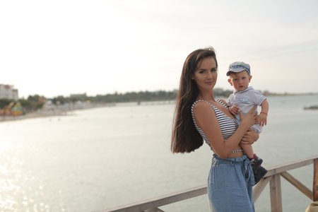 A beautiful young woman, a brunette with long straight hair, a sweet smile, plays with her young son...