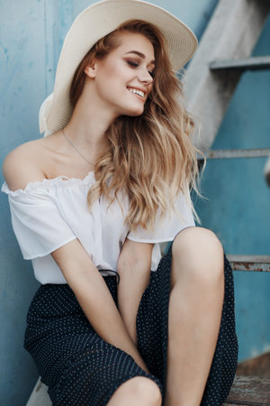 A beautiful young woman with long blond hair, gray eyes, clean skin and pink lips in a straw hat...