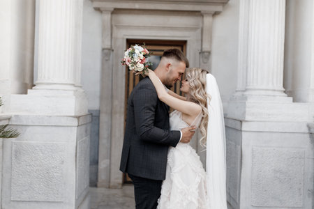 Portrait happy of a wedding couple which is walking near the old renaissance palace. The bride and groom in the summer on the wedding day together on the territory of the wedding palace in the open airの写真素材