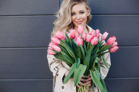 Beauty glamor girl with Spring tulips Flower bouquet. Beautiful young woman with a Bunch of colorful Tulip flowers outdoors. Happy model posing with spring flowers. Valentine's Day. Gift.Women's Dayの写真素材