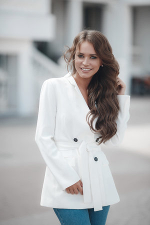 A young, beautiful, fashionable woman in the open air on a summer sunny day, long curly blond hair...