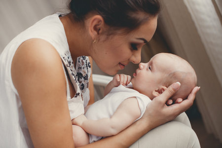 Mother and child on a white bed. Parent and small child rest at home. Family having fun together....