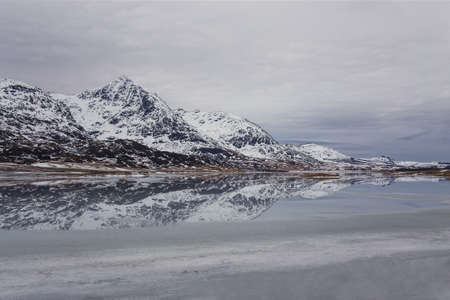 mountains and their reflection in a frozen lakeの写真素材
