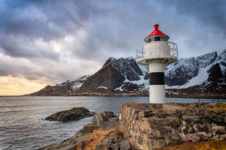 Photograph in SakrisÃ¸y, Lofoten with a lighthouse in the foreground, at sunset on a cloudy dayの写真素材