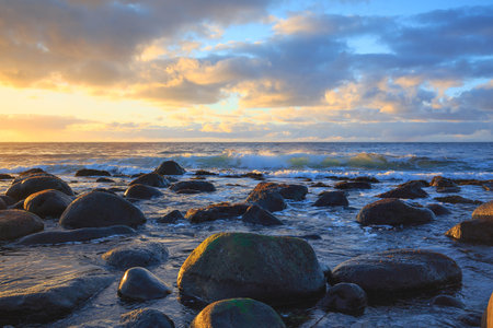 sunset with clouds from the shore of the beach full of stones or pebbles