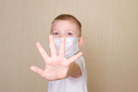 The concept of coronavirus, self-isolation, and quarantine. A boy in a disposable medical mask with his arm outstretched.の写真素材