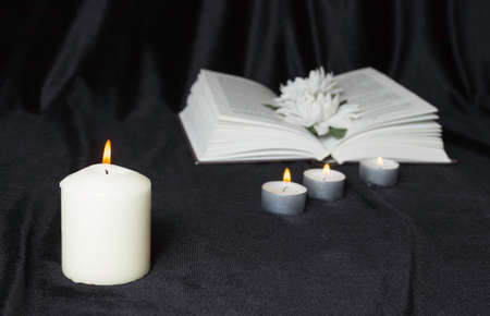 Condolence card. A white memorial candle with white flowers and an open book. The funeral, the sadness.の写真素材