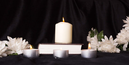 Condolence card. A white memorial candle with white flowers and book. The funeral, the sadness.