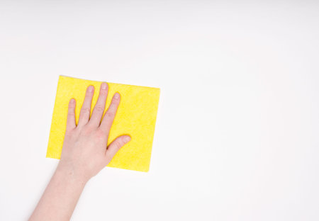 Part of the hand with a yellow cloth for dusting and removing dirt. Cleaning, white background, free...