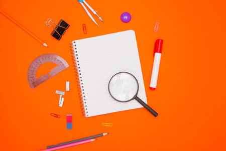 The concept of training and education. An empty checkered notebook and stationery on an orange...