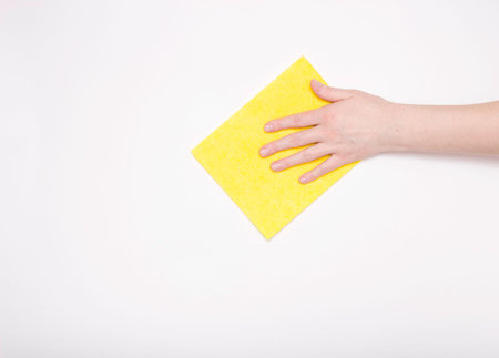 Part of the hand with a yellow cloth for dusting and removing dirt. Cleaning, white background, free...