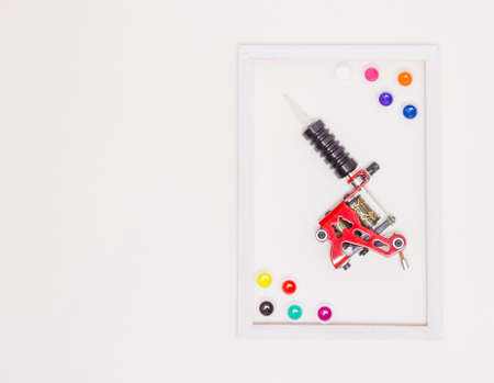 tattoo machine on a white background, white frame, free space for text, colored tattoo ink in plastic jars. The view from the top.の写真素材