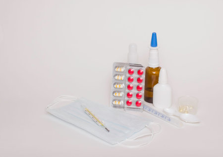 Medicines, tablets, thermometer, medical masks on a white background. Free space for text, side view.の写真素材