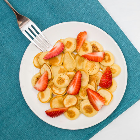 Trendy home breakfast with tiny pancakes, bananas and strawberry on a colored towel. View from above.の写真素材