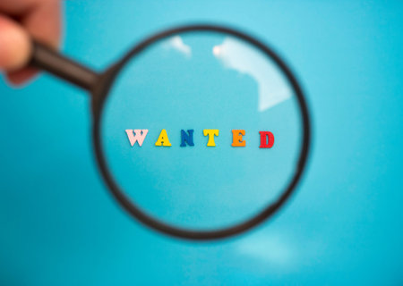 Search for employees to work. The word WANTED in colored wooden letters on a blue background through...