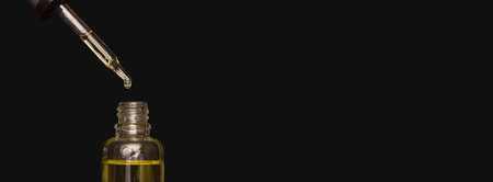 Pipette with cosmetic oil on a black background. A bottle of cosmetics. Skin, hair, and body care. Spa. Banner, free space for text.の写真素材