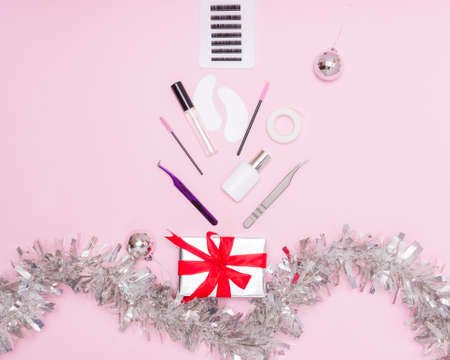 New year and Christmas for the masters of eyelash extension. Things for the work of lashmakers, artificial eyelashes, tweezers, combs, brushes for extended eyelashes. Top view, pink background, free space for text.の写真素材