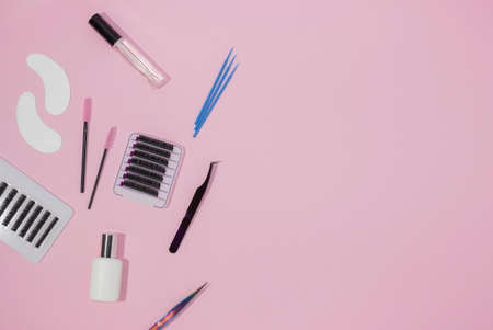 Tools for eyelash extensions on a pink background, free space for text, top view. Artificial eyelashes, tweezers, microbrushes, patches and brushes for lashmaker.の写真素材