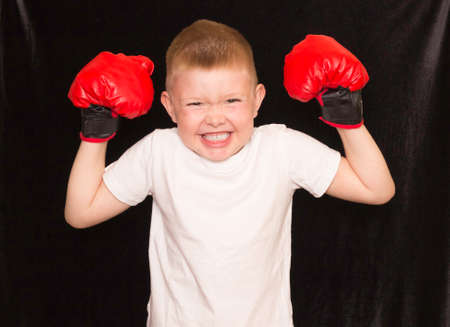Children's Boxing, sports. A boy in a white t-shirt with red Boxing gloves on a black background.の写真素材