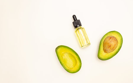Glass bottle with pipette and avocado oil and avocado fruit on a light background, top view, free space for text. Face and body skin care and healthy nutrition.の写真素材