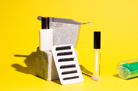 Tools for eyelash extension on stones on a yellow background. Artificial eyelashes, lashmaker tools.