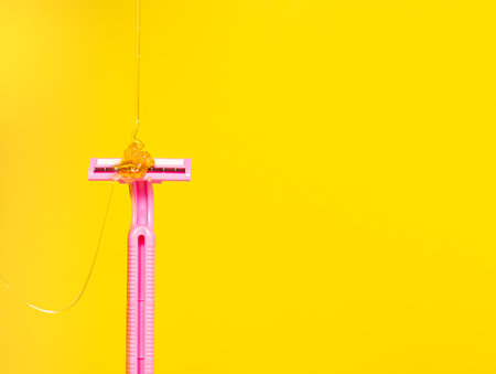 Sugar paste for hair removal flows on the razor. Razor vs epilation, depilation, sugaring, body care. Yellow background, free space for text.の写真素材