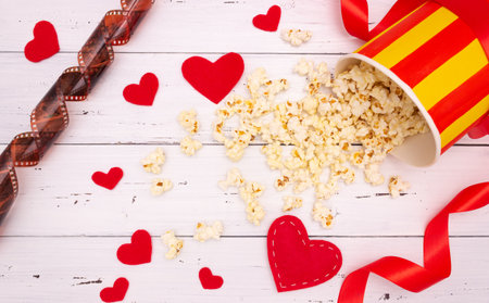 Popcorn, red hearts and ribbon on a white wooden background. valentine's day, movie theater.の写真素材