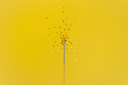 Confetti stars and sparkler sticks on a yellow background. The view from the top. The concept of the celebration.の写真素材
