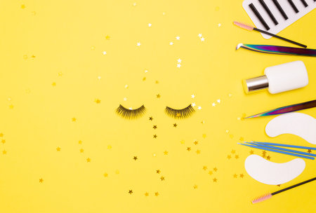 Eyelash extension tools and artificial eyelashes on a yellow background. The view from the top.の写真素材