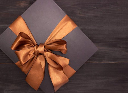 Black gift box with satin ribbon on the tableの写真素材