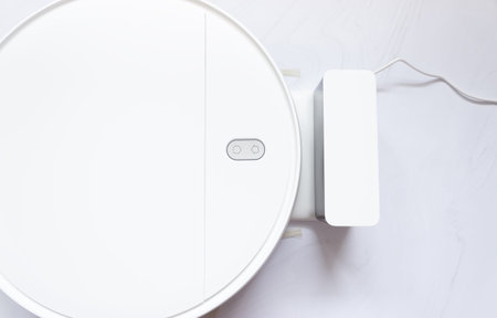 Part of a white robot vacuum cleaner and charger, top view.