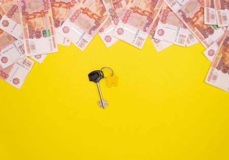 Five thousand Russian rubles in denominations on a yellow background and the keys to the apartment. The concept of buying a home, mortgage. Top view, free space for textの写真素材