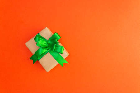 Gift box with a green bow on an orange backgroundの写真素材