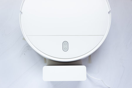 Part of a white robot vacuum cleaner and charger, top view.の写真素材
