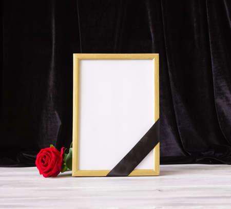 The concept of memory, funerals and condolences. Photo frame with black mourning ribbon and flower.の写真素材