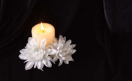 The concept of remembrance, funerals, and condolences. Candle and white flowers, free space for textの写真素材