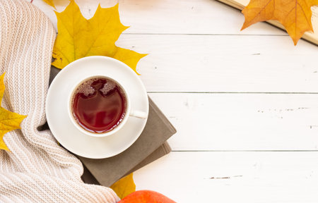 Autumn flatley. A cup of tea, yellow maple leaves, books, and a knitted thing, copyspaceの写真素材