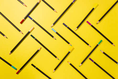 Colored pencils are graphically laid out on a yellow background, top view, hard shadows. Abstractionの写真素材