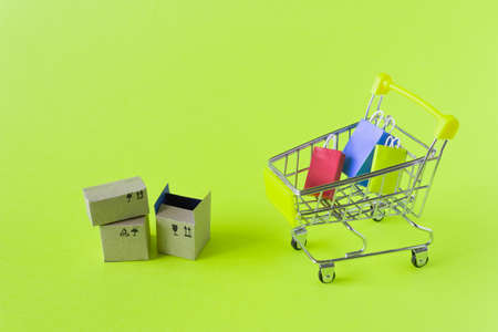 A small grocery cart with boxes and bags on a green background.の写真素材